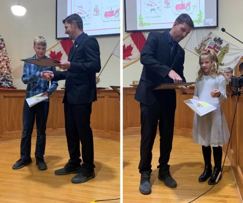 A boy and a girl each receiving an award from a man in a black suit.