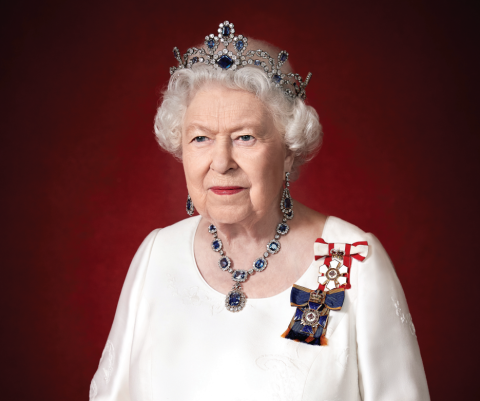Queen Elizabeth wearing a tiara, sapphire jewellery, and a white dress with medals.