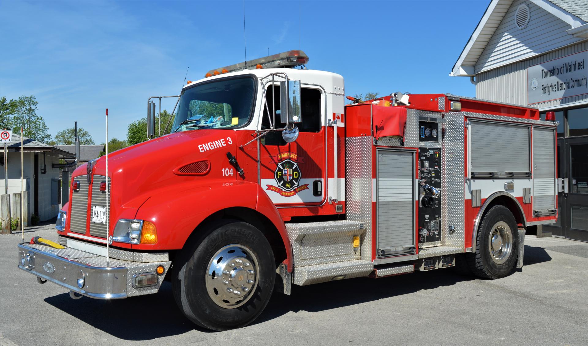 Red fire engine marked 104 with Wainfleet Fire Department logo, parked outside.