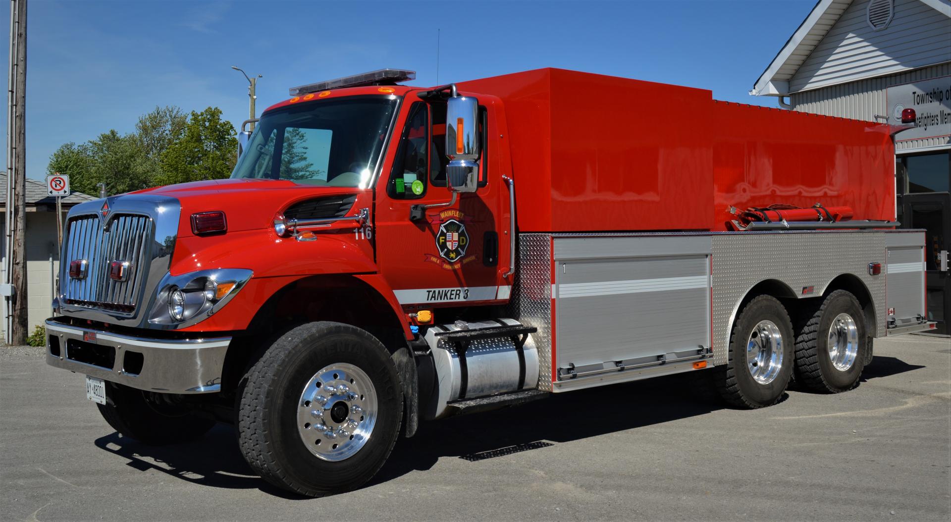 Red fire tanker marked 116 with Wainfleet Fire Department logo, parked outside.