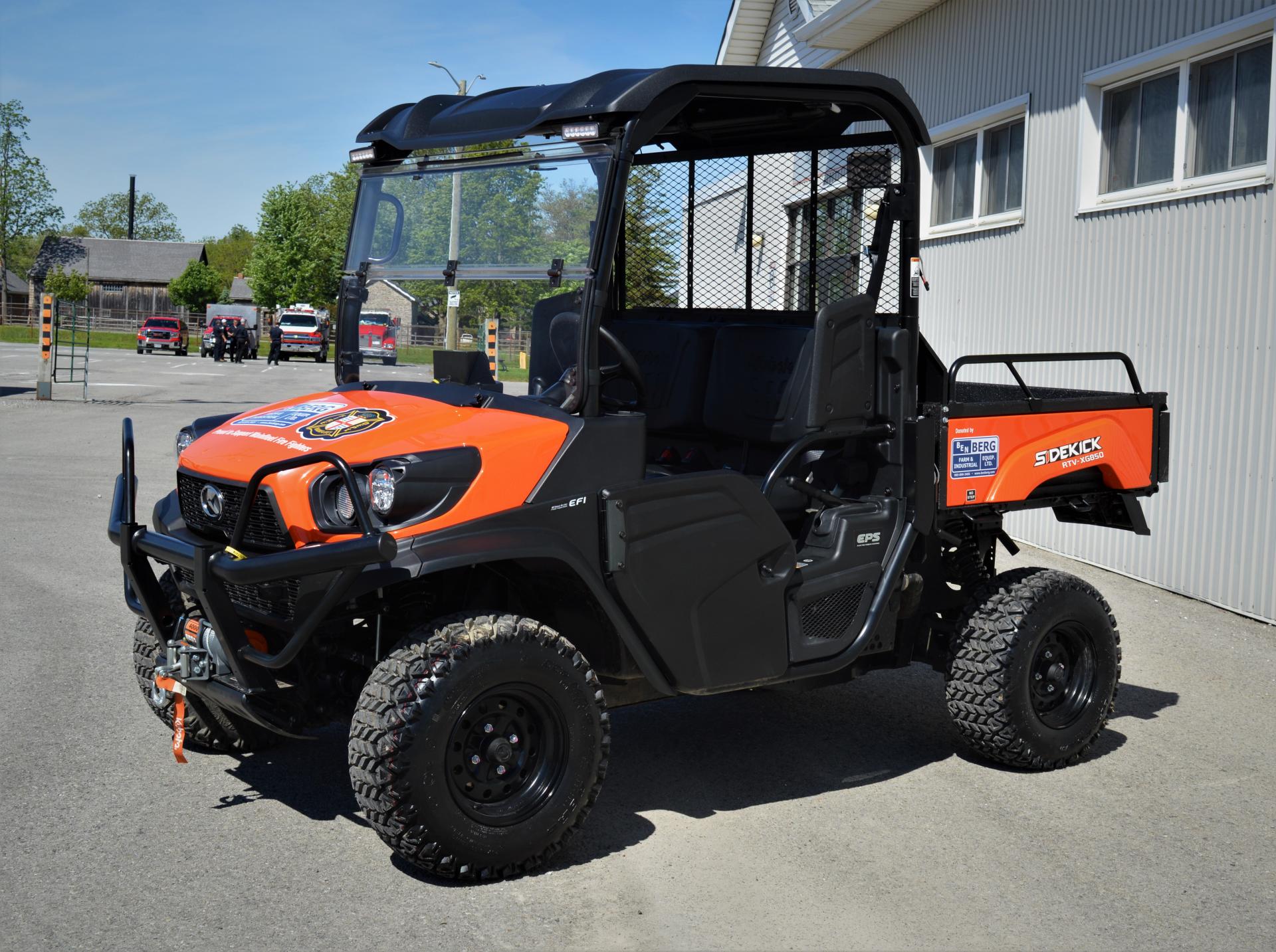Orange and black off-road utility vehicle with Wainfleet Fire Department logo, parked outside.