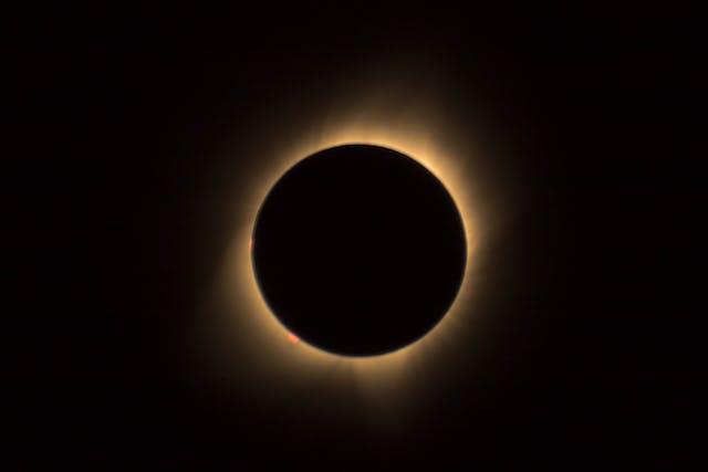 A total solar eclipse with the moon completely blocking the sun, leaving only the sun's glowing corona visible as a bright ring around the dark silhouette of the moon.